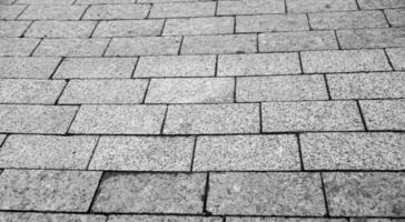 stad väg trottoar tillverkad av tegelstenar och stenar, väg textur i detalj svart och vit bakgrund foto