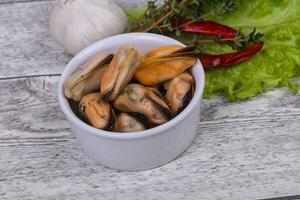 inlagda musslor i skålen serveras peppar, vitlök och sallad foto