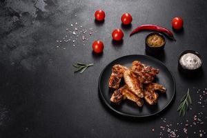 grillade kryddiga kycklingvingar på en mörk bakgrund med kryddor och örter