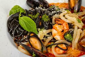 svart tagliatelle pasta tillverkad med bläckfisk bläck med räkor, mussla och bläckfisk foto