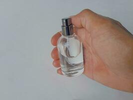 en mannens hand elegant innehar en glas parfym flaska på en vit bakgrund foto
