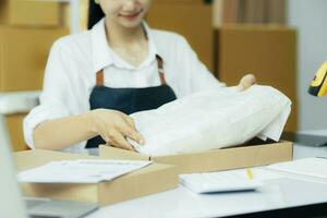 små företag ägare förpackning kläder i de låda på arbetsplats. foto