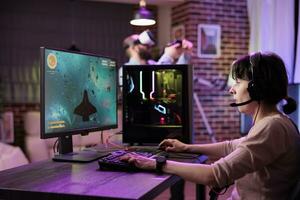 gamer använder sig av professionell kvalitet nivå gaming uppstart till undvika störande eftersläpning medan spelar esports turneringar. kvinna avkopplande i rgb lampor lägenhet spelar verkan skytte TV-spel sent på natt foto