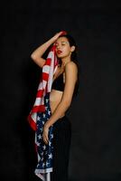 porträtt kvinna idrottare insvept i amerikan flagga mot svart bakgrund foto