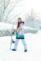 ung kvinna innehav snowboard på henne axlar foto