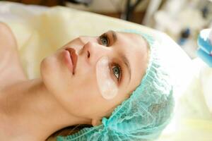 kvinna kosmetolog framställning kosmetisk ansiktsbehandling mask till de kvinna klient foto