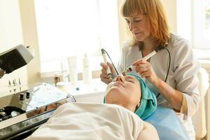 kosmetolog gör de procedur mikroström terapi i en skönhet salong foto