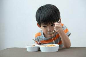 asiatisk pojke äter spaghetti på de tabell. foto
