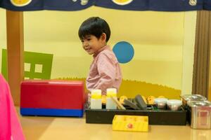 liten asiatisk pojke spelar kock tjänande mat foto