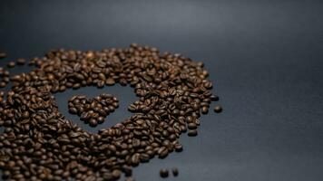 högen av kaffe bönor på svart bakgrund foto