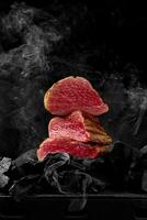 skivad sällsynt kalvkött fläskkarré på kol på svart bakgrund i vit rök foto