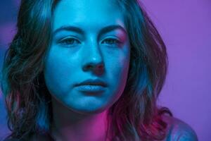 blå och lila färgad porträtt av skön tonåring flicka med fräknar. foto