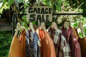 garage försäljning, kläder för försäljning hängande på galge utomhus. foto