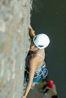en flicka klättrar en sten. kvinna engagerad i extrem sport. foto