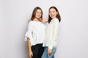 två skrattande flickor i vit tom t-tröjor ser in i de kamera foto