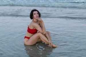 sexig tillbaka av en skön kvinna i röd bikini på hav bakgrund foto