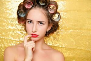 skön flicka i hår papiljotter isolerat på guld foto