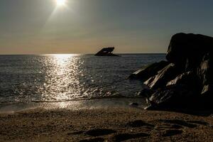 solnedgång strand i cape Maj ny jersey var du kan skaffa sig en bra se av de Sol gående ner tvärs över de hav och de bukt. de reflexion av de Sol på de vatten med de nedsänkt fartyg utseende så skön. foto