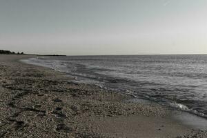 Söt se av detta strand som de vågor kom i till de Strand. de vatten ser lugna och de sand en gyllene brun. de skön himmel med Nej moln i webbplats gör detta se tycka om en skön sommar dag. foto