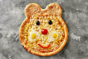 björnformad pizza för barn med mozzarella, majs, körsbär tomat, klocka peppar, oliver, vaktel ägg och sesam foto