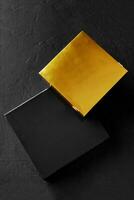 två svart och gyllene kartong lådor på texturerad yta foto
