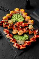 uppsättning av rullar, nigiri sushi och gunkan maki med lax på svart skiffer styrelse foto