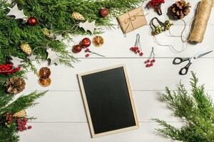 enbär grenar med en jul dekor. jul, ny år bakgrund. barr- grenar av enbär och svart skrivning styrelse. topp se, platt design. foto