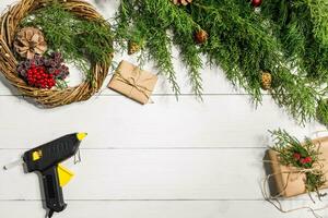 göra en jul krans med din egen händer. gran gren, jul krans och gåvor på en vit trä- bakgrund foto
