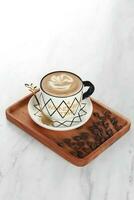 cappuccino kaffe eras i en vit kopp med svart rader med kaffe bönor. isolerat i vit bakgrund foto
