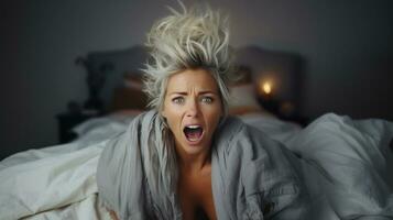 ung kvinna skrikande i säng efter vakna upp i de morgon. foto