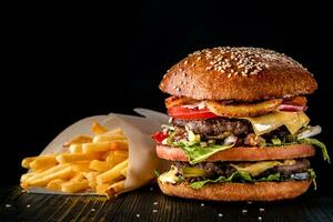 hantverk nötkött burger och franska frites på trä- tabell isolerat på svart bakgrund. foto