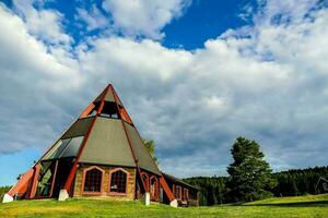 en kyrka med en triangel- tak på en gräs- kulle foto