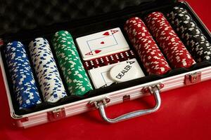 poker uppsättning i metall resväska. riskabel underhållning av spelande. topp se på röd bakgrund foto