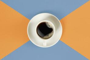 en kopp av svart kaffe på orange och blå bakgrund. se från ovan. foto
