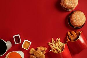 två hamburgare och franska pommes frites, såser och drycker på röd bakgrund. snabb mat. topp se, platt lägga med copy foto