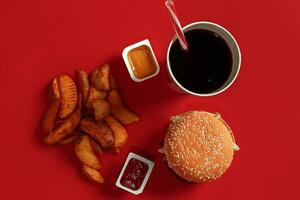 burger och pommes frites. hamburgare och franska frites i röd papper låda. snabb mat på röd bakgrund. foto