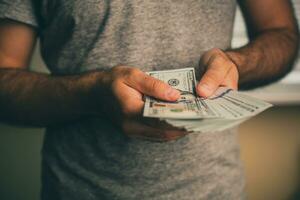 en man innehar dollar i hans händer foto