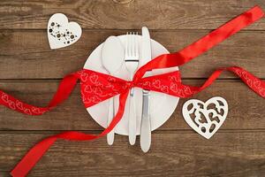 hjärtans dag bakgrund, vit tallrik, gaffel, kniv, tejp hjärtan, två hjärta på gammal trä- tabell foto