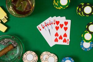 spelande, förmögenhet och underhållning begrepp - stänga upp av kasino pommes frites, whisky glas, spelar kort och cigarr på grön tabell yta foto