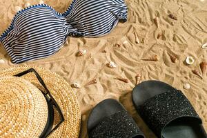 sommar bikini och Tillbehör eleganta strand uppsättning, strand bikini sommar utrusta och hav sand som bakgrund, topp se, begrepp foto