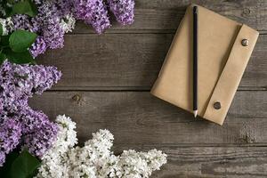 lila blomma på rustik trä- bakgrund med anteckningsbok för hälsning meddelande. topp se foto