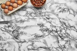 närbild skott. topp se av en bakning Ingredienser och köksutrustning på de marmor tabell bakgrund. foto