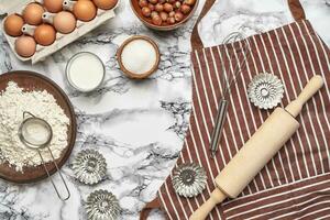 närbild skott. topp se av en bakning Ingredienser och köksutrustning på de marmor tabell bakgrund. foto