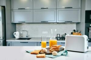 brödrost med färsk rostat bröd, ägg och glas av orange juice på en ljus kök tabell foto