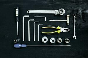 rycka uppsättning av tång uttag skruvnyckel och skruvmejsel verktyg på svart trä- bakgrund foto