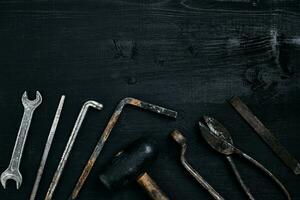 gammal, rostig verktyg liggande på en svart trä- tabell. hammare, mejsel, metall sax, rycka. foto