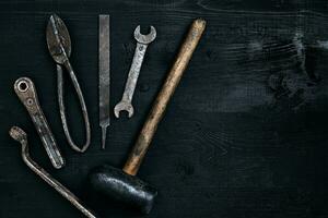 gammal, rostig verktyg liggande på en svart trä- tabell. hammare, mejsel, metall sax, rycka. foto