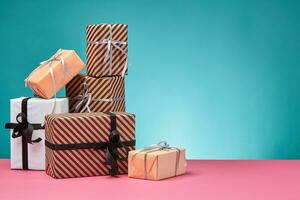 annorlunda storlekar, färgrik, randig och enkel papper gåva lådor bunden med band och bågar på en rosa yta och blå bakgrund. närbild, kopia Plats. foto