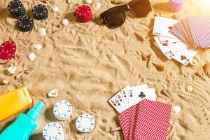 beachpoker. pommes frites och kort på de sand. runt om de snäckskal, solglasögon och solbränna grädde. topp se foto