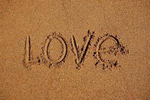ordet kärlek skriven på sanden foto
